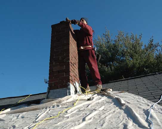 Man starting to demolish brick chimney