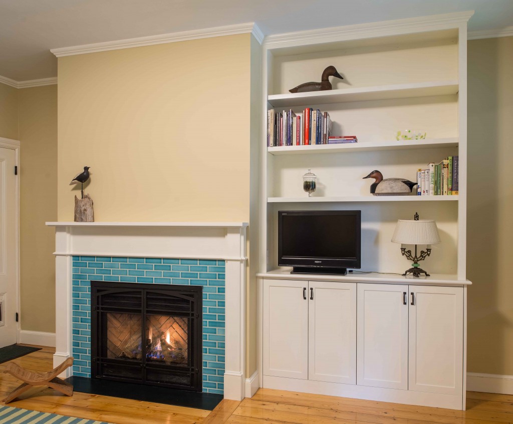 wood mantel, gas fireplace, tiled surround, and built-in bookcase