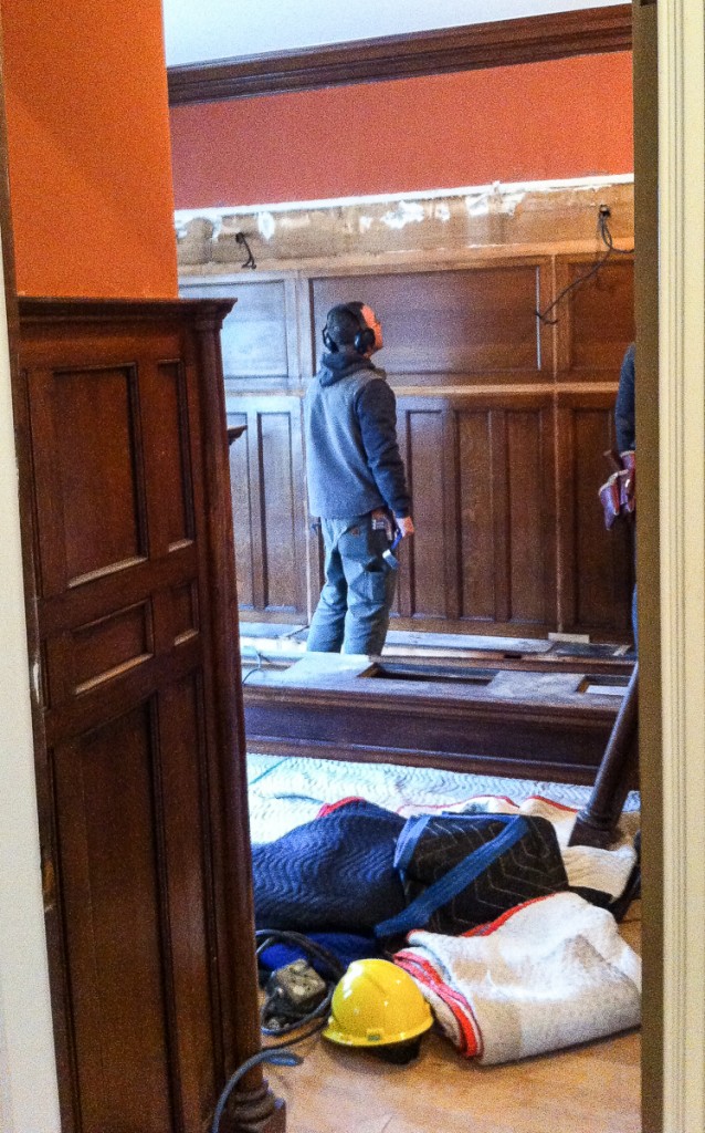 two carpenters dismantling oak library cabinets