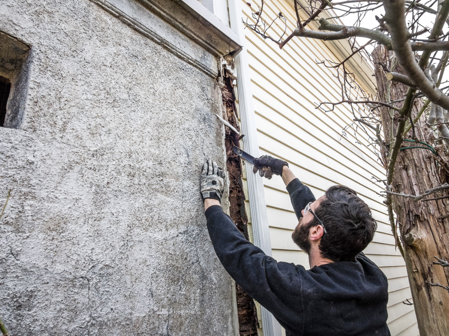 Carpenter burying his pry bar into a rotten corner post