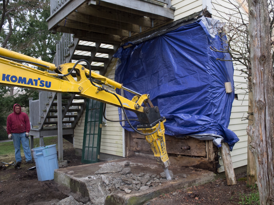 Using a hydraulic hammer to break apart concrete slab and foundation